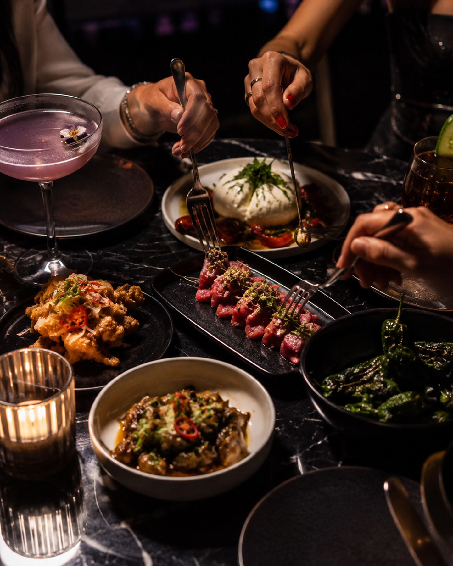 Shared plates and cocktails spread across a marble table